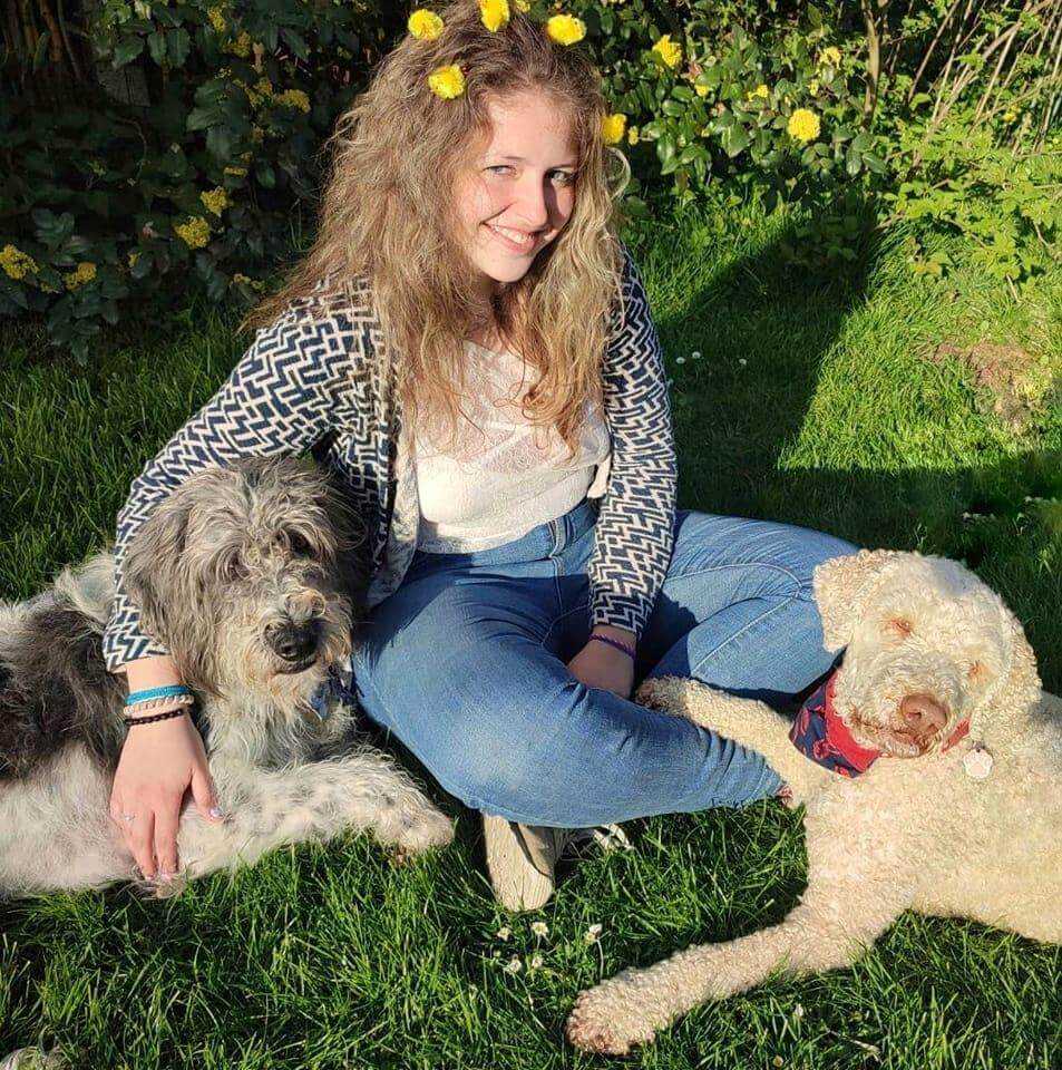 Bénévole avec ces deux chiens, Arthur et Ubi, assise dans l'herbe
